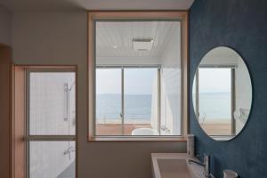 a bathroom with a mirror and a sink and a window at ALFACIO RESORT STAY ITOSHIMA in Itoshima