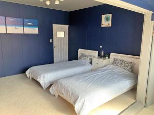 Ramjet Sotoura Beach House Shimoda في شيمودا: سريرين في غرفة نوم بجدران زرقاء