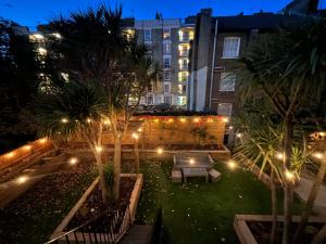 a courtyard at night with palm trees and lights at Swinton Hotel in London
