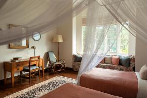 a bedroom with two beds and a desk and a window at Ceylon Tea Trails in Hatton