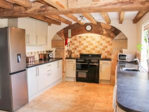 una cocina con armarios blancos y electrodomésticos negros en Camden Cottage, en Kidderminster