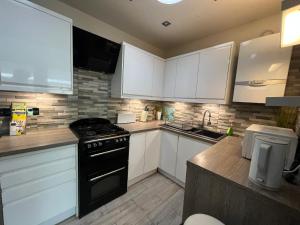 a kitchen with white cabinets and a black stove top oven at Bungalows near Sandbanks Beach in Poole