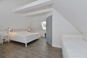 a white bedroom with a bed and a desk at STöRTEBEKER APPARTEMENTS - "BLAUES HAUS" in Ralswiek
