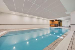 a large swimming pool with blue water in a building at Adina Serviced Apartments Canberra Kingston in Canberra