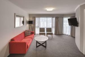 a living room with a red couch and a table at Adina Serviced Apartments Canberra James Court in Canberra