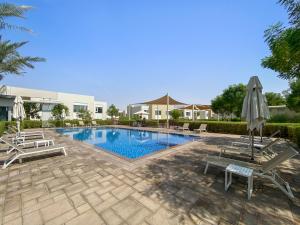 a swimming pool with two chairs and an umbrella at Spacious & Private Townhome - 5 mins drive to Al Maktoum Airport in Dubai