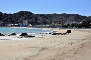 a beach with people walking on the sand and the water at Sotoura Beach House Shimoda - Less thank 1 min walk to Sotoura Beach! in Shimoda
