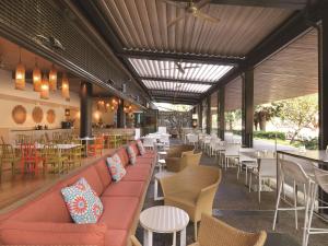 a restaurant with a red couch and tables and chairs at Adina Apartment Hotel Darwin Waterfront in Darwin