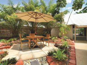 einen Tisch und Stühle mit Sonnenschirm in einem Garten in der Unterkunft Travelodge Resort Darwin in Darwin