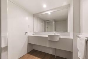 a white bathroom with a sink and a mirror at Travelodge Resort Darwin in Darwin