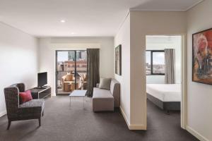 Habitación de hotel con cama y sala de estar. en Adina Apartment Hotel Perth Barrack Plaza, en Perth