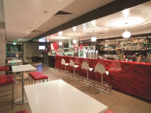 Adina Apartment Hotel Perth في بيرث: مطعم بطاولات بيضاء وكراسي وبار