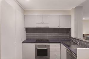 a white kitchen with a stove and a sink at Adina Apartment Hotel Perth Barrack Plaza in Perth