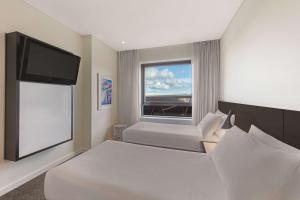 Adina Apartment Hotel Perth في بيرث: غرفة نوم بسرير وتلفزيون بشاشة مسطحة