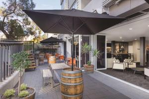 a patio with a table and an umbrella at Rendezvous Hotel Perth Central in Perth