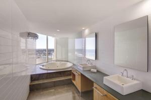 a bathroom with two sinks and a large mirror at Rendezvous Hotel Perth Scarborough in Perth