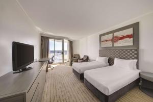 パースにあるランデブー ホテル パース スカボローのベッド2台、薄型テレビが備わるホテルルームです。