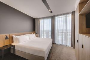 a bedroom with a white bed and a large window at Vibe Hotel Canberra in Canberra