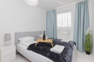 ein weißes Schlafzimmer mit einem Bett und einem Tisch darauf in der Unterkunft Gdynia Nasypowa Apartments with Parking by Renters in Gdynia