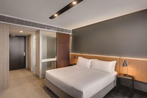 Vibe Hotel Canberra في كانبرا: غرفة نوم مع سرير أبيض كبير في غرفة
