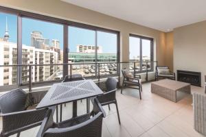 a balcony with tables and chairs and a view of the city at Adina Apartment Hotel Auckland Britomart in Auckland