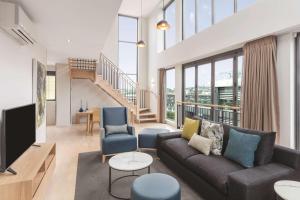 a living room with a couch and a tv at Adina Apartment Hotel Auckland Britomart in Auckland
