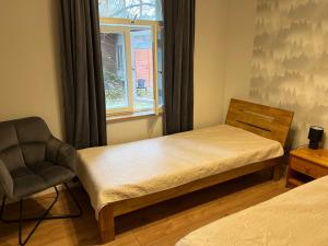 a bedroom with a bed and a chair and a window at Nõmme Apartments in Tallinn