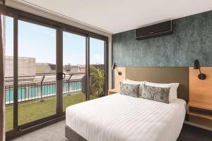 una camera con un grande letto e ampie finestre di Adina Apartment Hotel Auckland Britomart ad Auckland