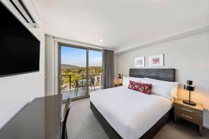 堪培拉Adina Serviced Apartments Canberra Dickson的一间酒店房间，里面有一张床和一扇大窗户。