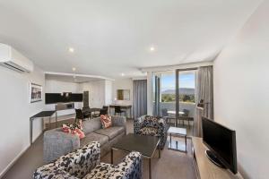 Adina Serviced Apartments Canberra Dickson في كانبرا: غرفة معيشة بها أريكة وكراسي وتلفزيون