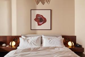 a bedroom with a bed with white sheets and two lamps at The Hoxton, Brussels in Brussels