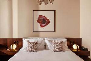 a bedroom with a bed with two lamps and a picture at The Hoxton, Brussels in Brussels