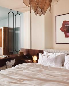 a bedroom with a bed with white sheets and a desk at The Hoxton, Brussels in Brussels