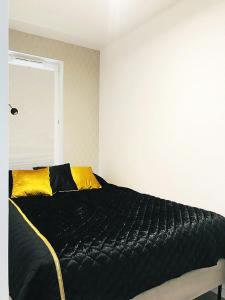 a bedroom with a large black bed with yellow pillows at Apartament 23 w Porto Łeba in Łeba