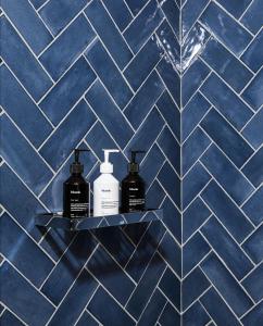 a blue tiled bathroom with two bottles of soap at The Hoxton, Brussels in Brussels