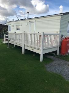 a mobile home with a white deck and a house at L38 Caravan Mablethorpe With ramp and gated decking in Mablethorpe