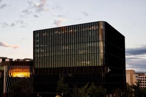 a tall black building with a sunset in the background at A by Adina Canberra in Canberra