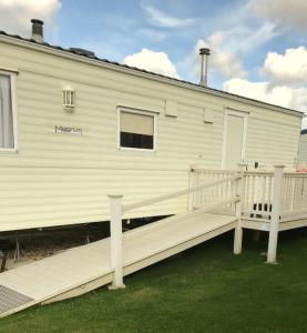 a large white house with a large wooden deck at L38 Caravan Mablethorpe With ramp and gated decking in Mablethorpe