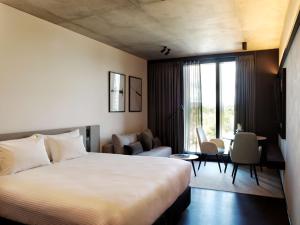 um quarto de hotel com uma cama e uma sala de estar em A by Adina Canberra em Camberra