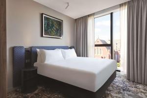 a large white bed in a room with a window at Adina Apartment Hotel Melbourne, Pentridge in Melbourne