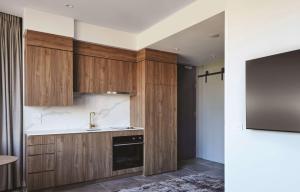 a kitchen with wooden cabinets and a sink at Adina Apartment Hotel Melbourne, Pentridge in Melbourne