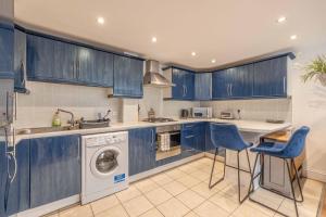 cocina con armarios azules, lavadora y secadora en Windsor centre Parkview, en Windsor