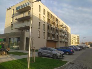 un estacionamiento con autos estacionados frente a un edificio en Mazurski Apartament, en Szczytno