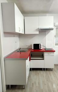 una cucina con armadi bianchi e piano di lavoro rosso di Estudio frente a Estación María Zambrano a Málaga