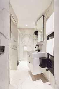 ein weißes Badezimmer mit einem Waschbecken und einem Spiegel in der Unterkunft Madrigal in Paris