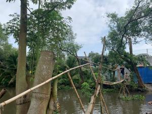 a man standing on a bamboo bridge over a river at Winter Spring Homestay Center in Can Tho