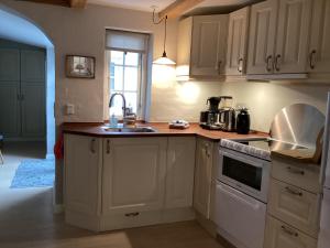 a kitchen with white cabinets and a sink at Dejligt lille byhus in Fåborg