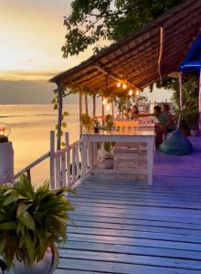 a wooden boardwalk on the beach at sunset at Secret Place Hotel and Restaurant in Haad Yao