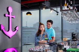 a man and woman standing behind a bar in a restaurant at SOJO Hotel Ha Long in Ha Long