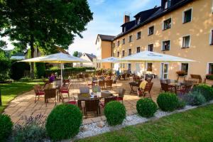 a patio with tables and umbrellas in front of a building at Erzgebirgshotel Freiberger Höhe in Eppendorf